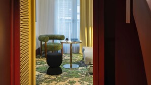 A modern hotel room with a unique green and black chair, a small round table, and a decorative floor lamp. - Hotel Maison Louise Lille Centre - Handwritten Collection (Lille)