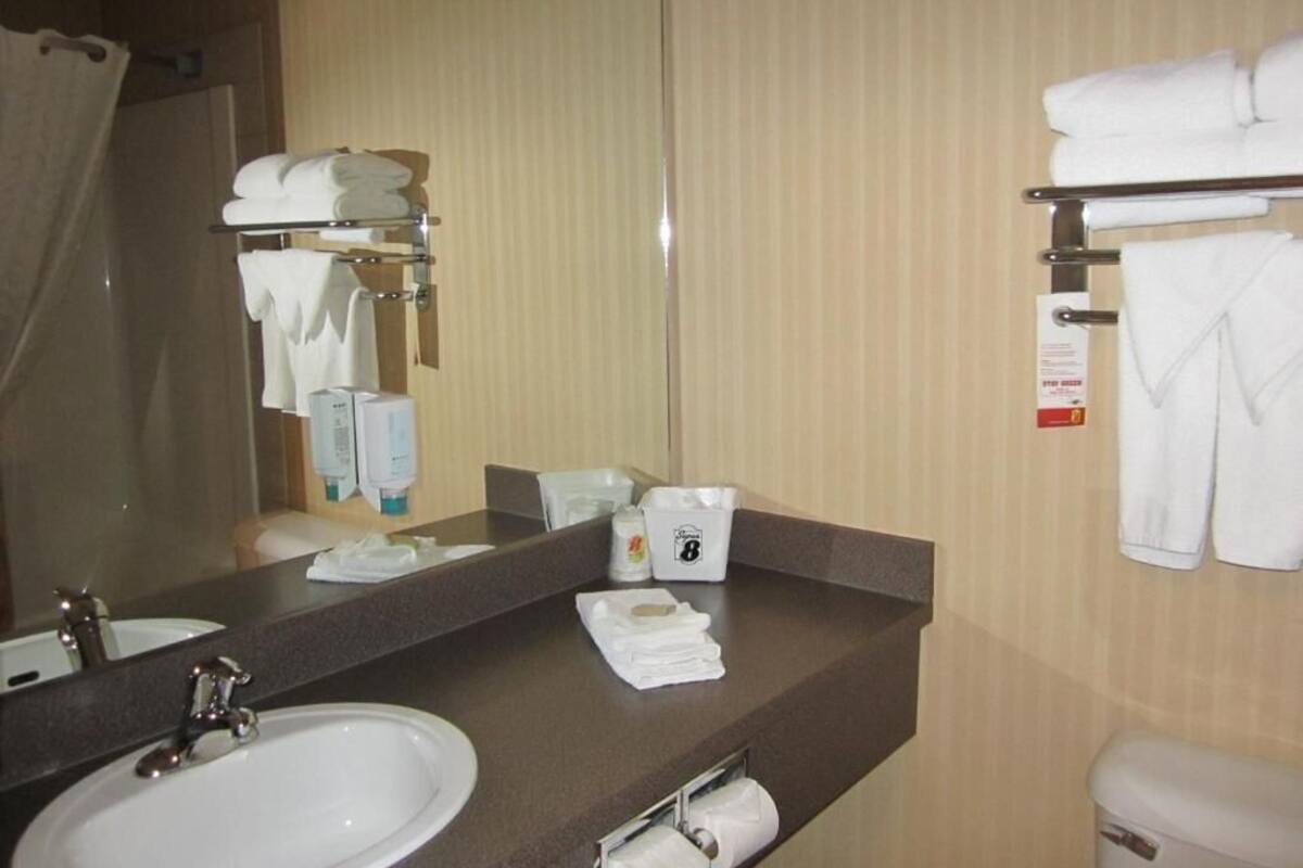 Une salle de bain d’hôtel équipée d’un lavabo, d’un miroir, d’un porte-serviettes et d’articles de toilette.