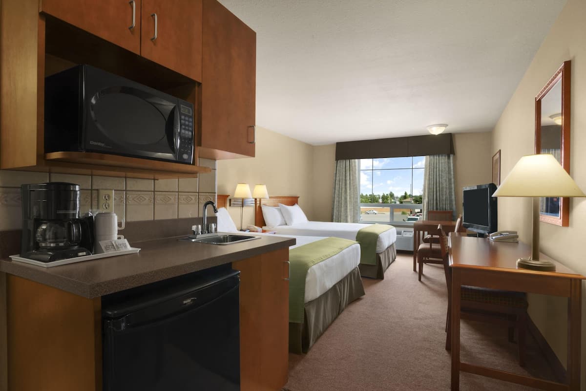 Une chambre d’hôtel équipée d’une kitchenette, d’un lit, d’un bureau et d’une télévision.