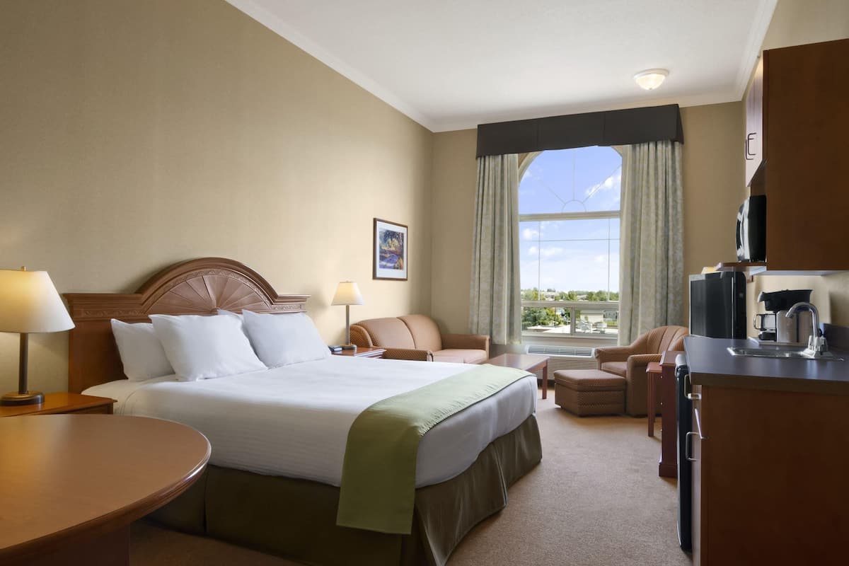 Une chambre d’hôtel avec un grand lit, un bureau équipé d’une machine à café, une chaise et une vue sur l’extérieur.
