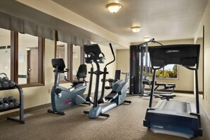 A gym with cardio machines, dumbbells, and a treadmill.
