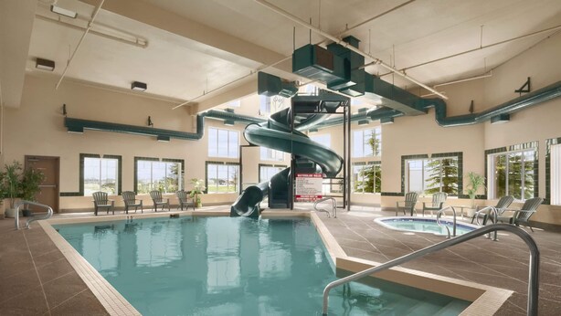 Una piscina interior con tobogán de agua, sillas de descanso y bañera de hidromasaje.