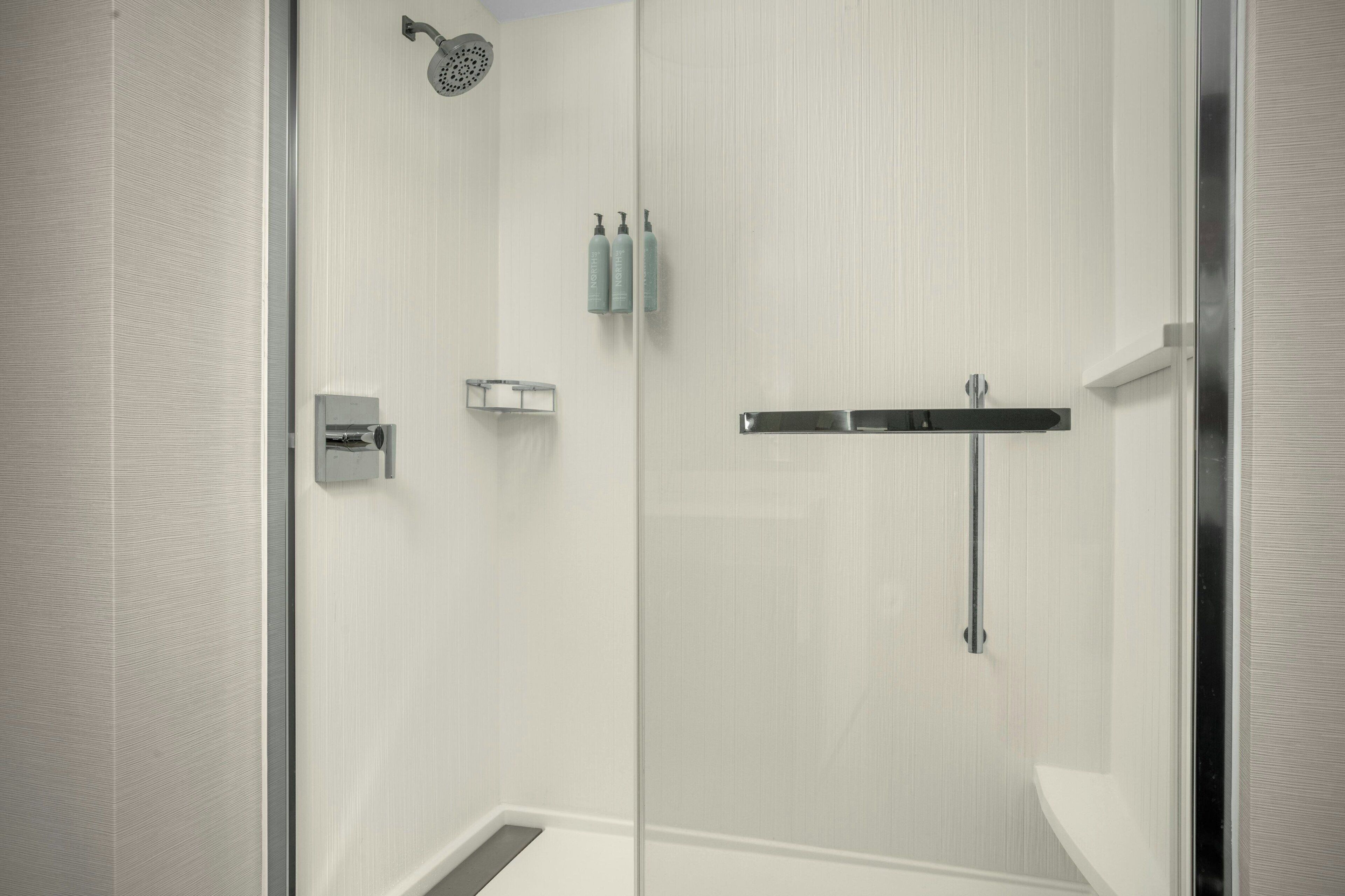 Une douche moderne dotée d’une porte en verre, d’un pommeau de douche à main et d’un robinet mural.