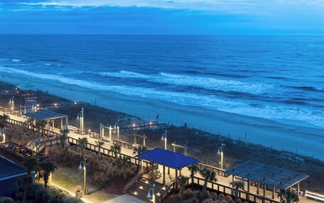 A coastal hotel with a boardwalk, beach access, and a gazebo.