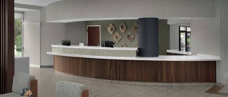 A reception area with a curved counter, seating, and a wall with decorative elements.