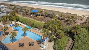 A resort with a swimming pool, beach access, and a boardwalk.