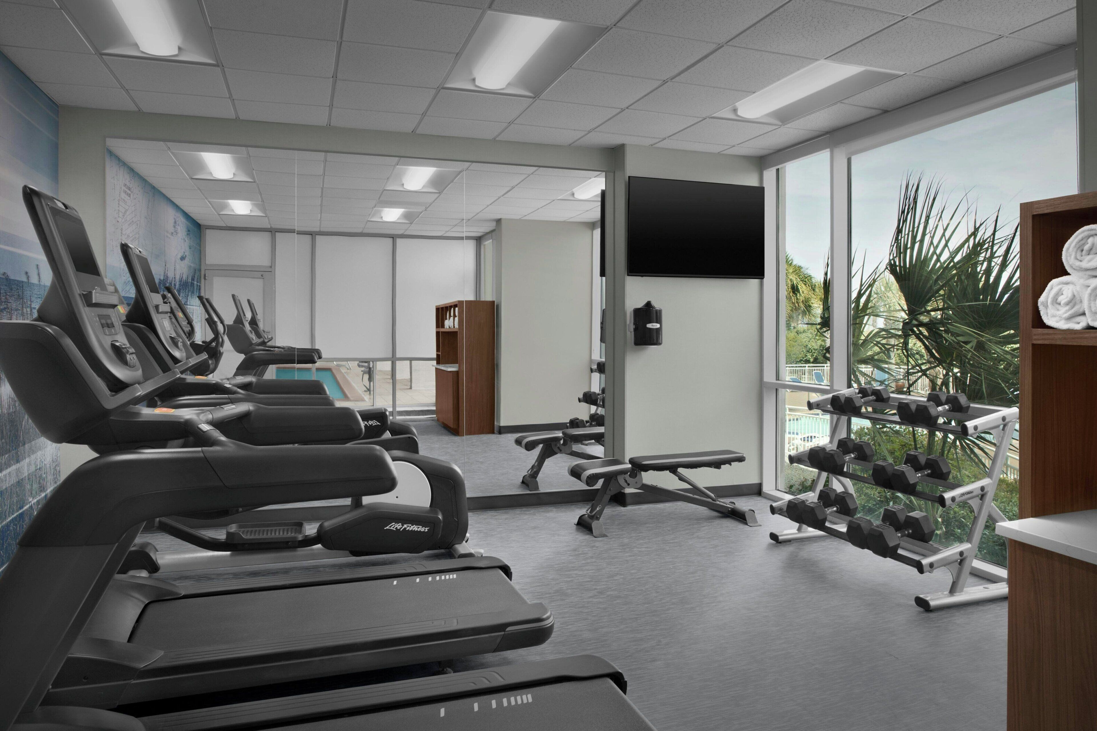 Ein Fitnessstudio mit Laufbändern, Gewichteinrichtungen und Hanteln.