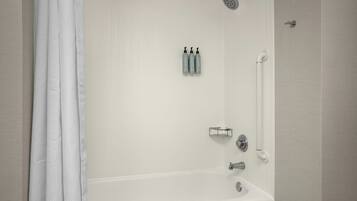 Un baño con bañera, ducha y dos botellas de champú en la pared.