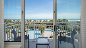 A balcony with a view of a pool and ocean.