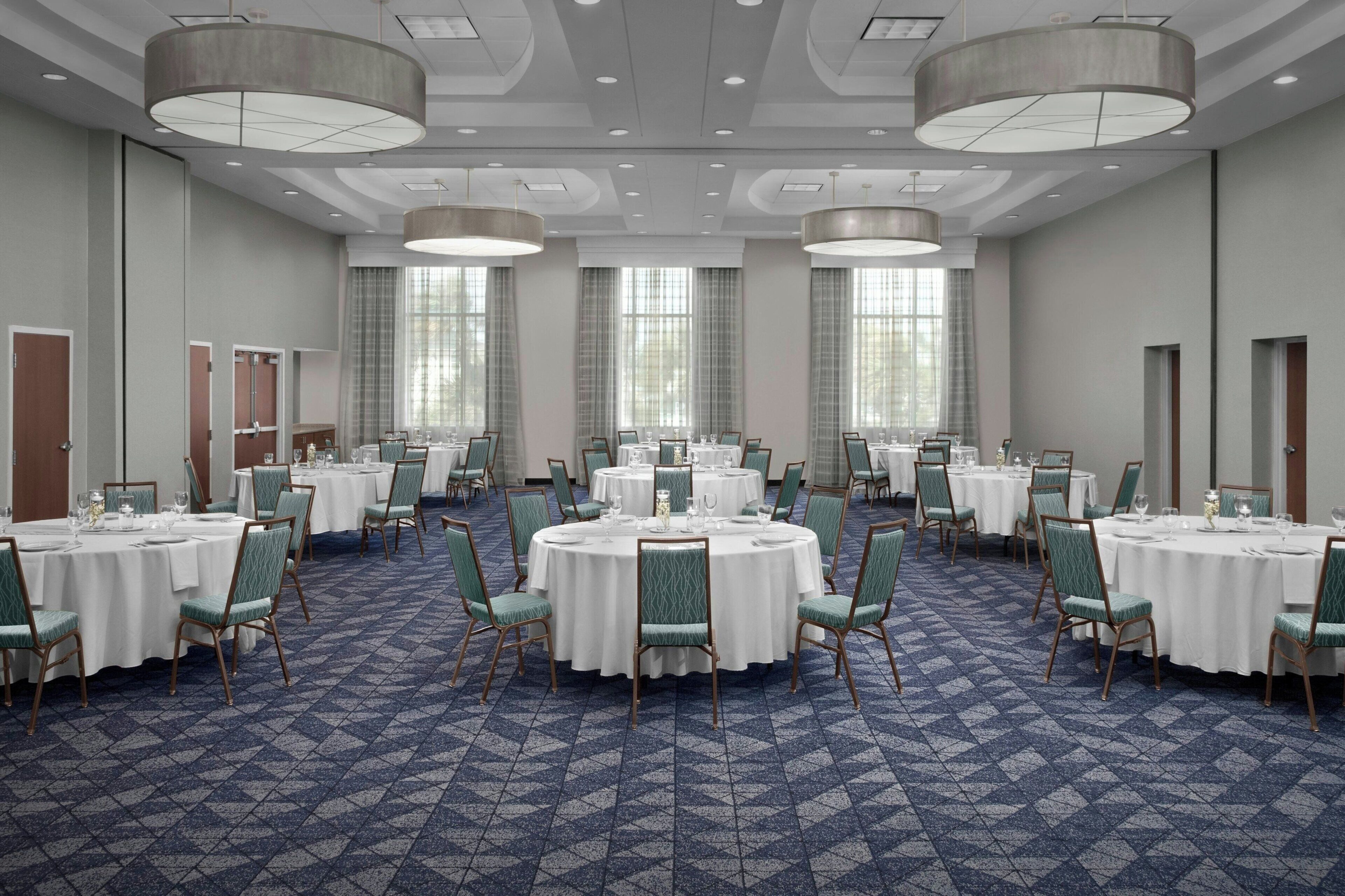 A conference room with round tables, green chairs, and a patterned carpet.