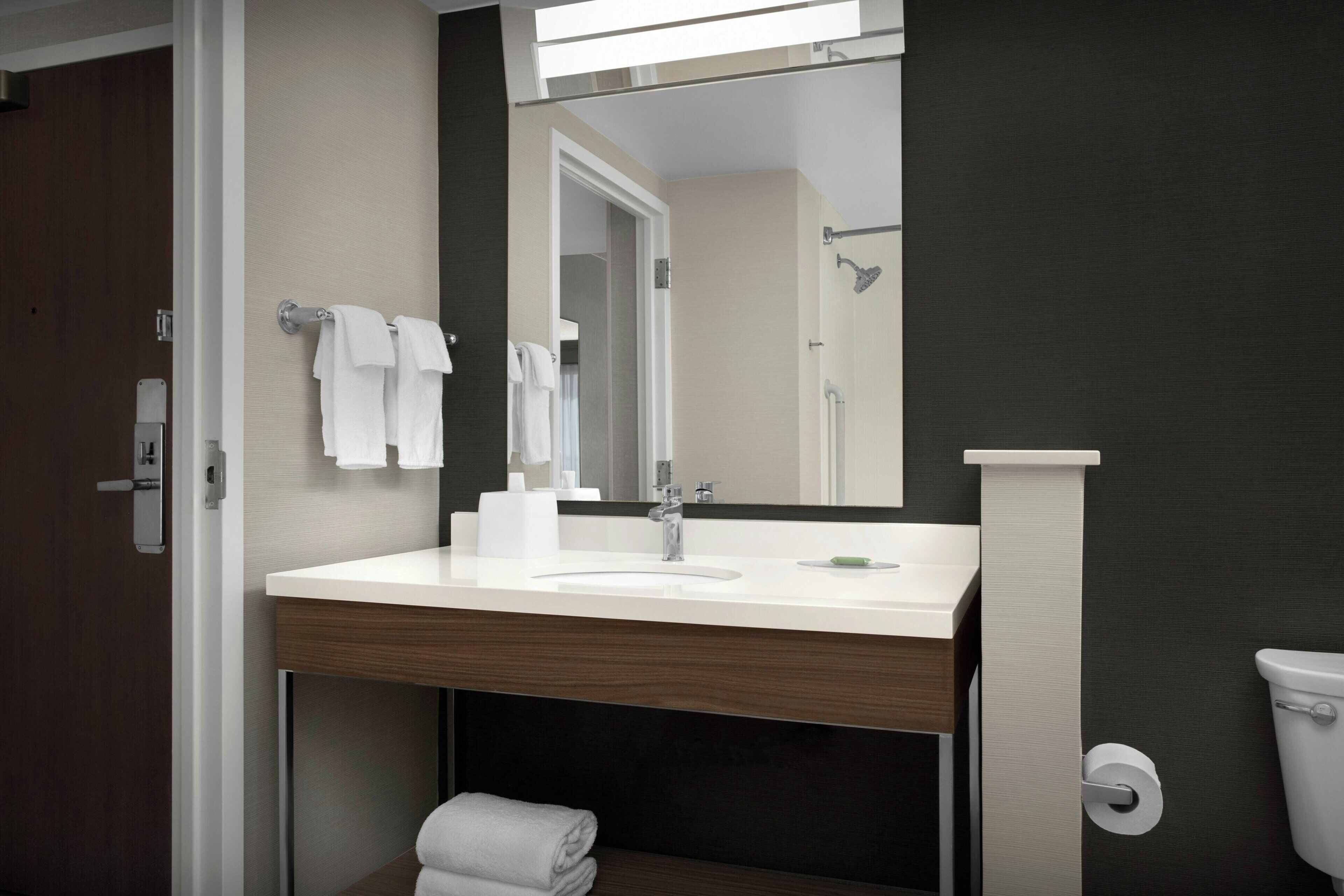 Un baño moderno con lavamanos, espejo y perchero blancos.