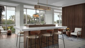 A modern kitchen with a large island, bar stools, and a hanging light fixture.