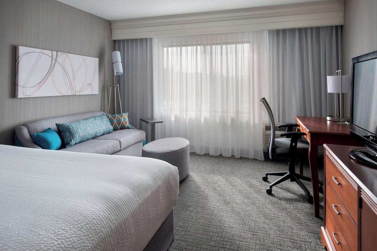Une chambre d’hôtel avec un grand lit, un canapé, un bureau et une télévision.