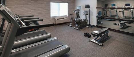 Un gimnasio moderno con cintas de correr, elípticas y pesas sueltas.