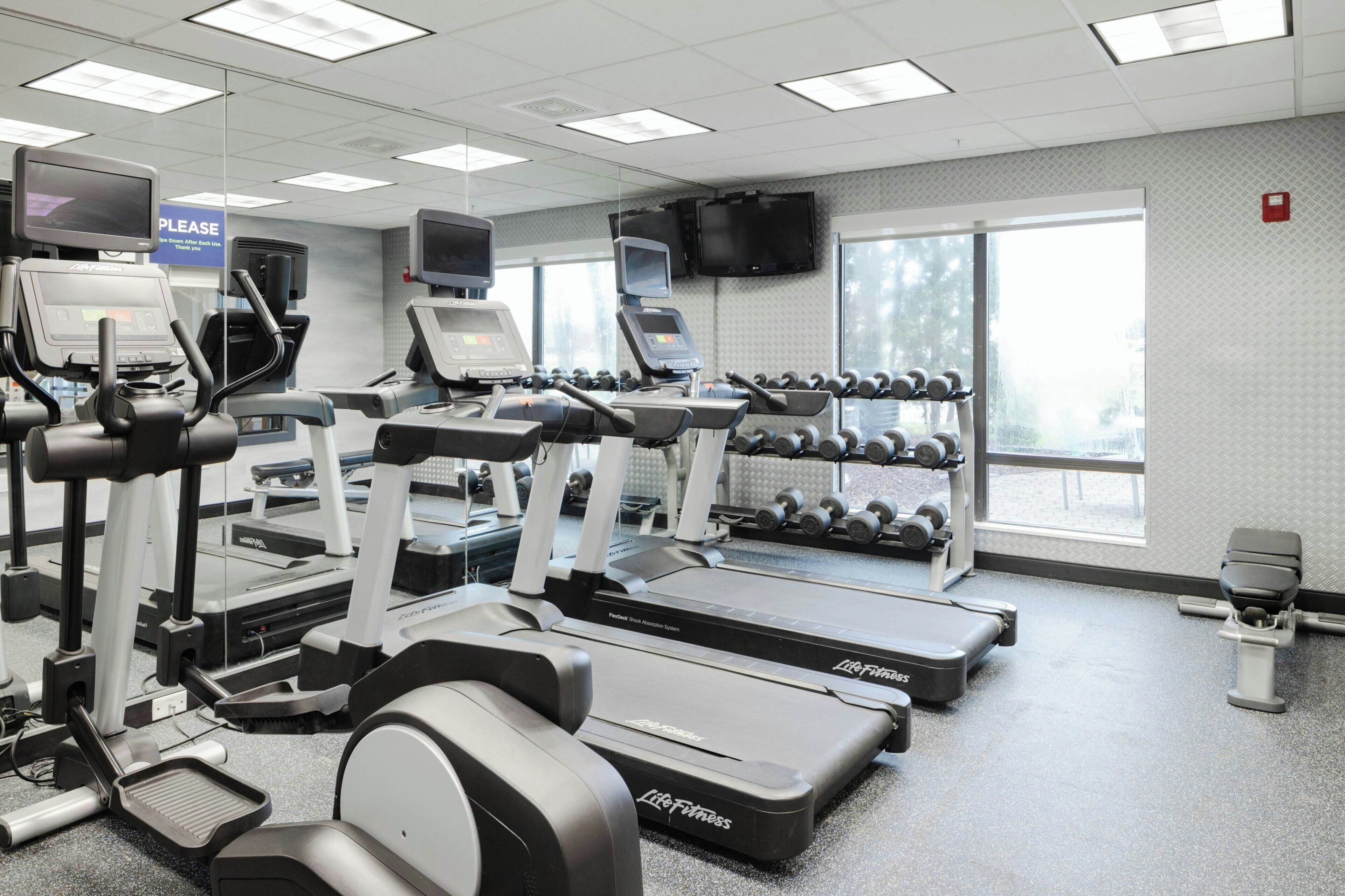A gym with treadmills, dumbbells, and exercise equipment.
