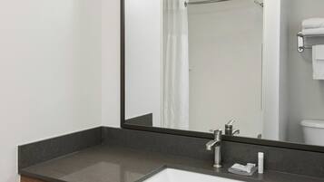 A modern bathroom with a large mirror, a sink, and a towel rack.