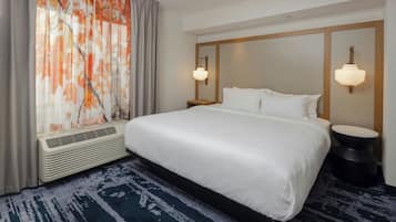 A hotel room with a large bed, a heater, a patterned rug, and a window with curtains.