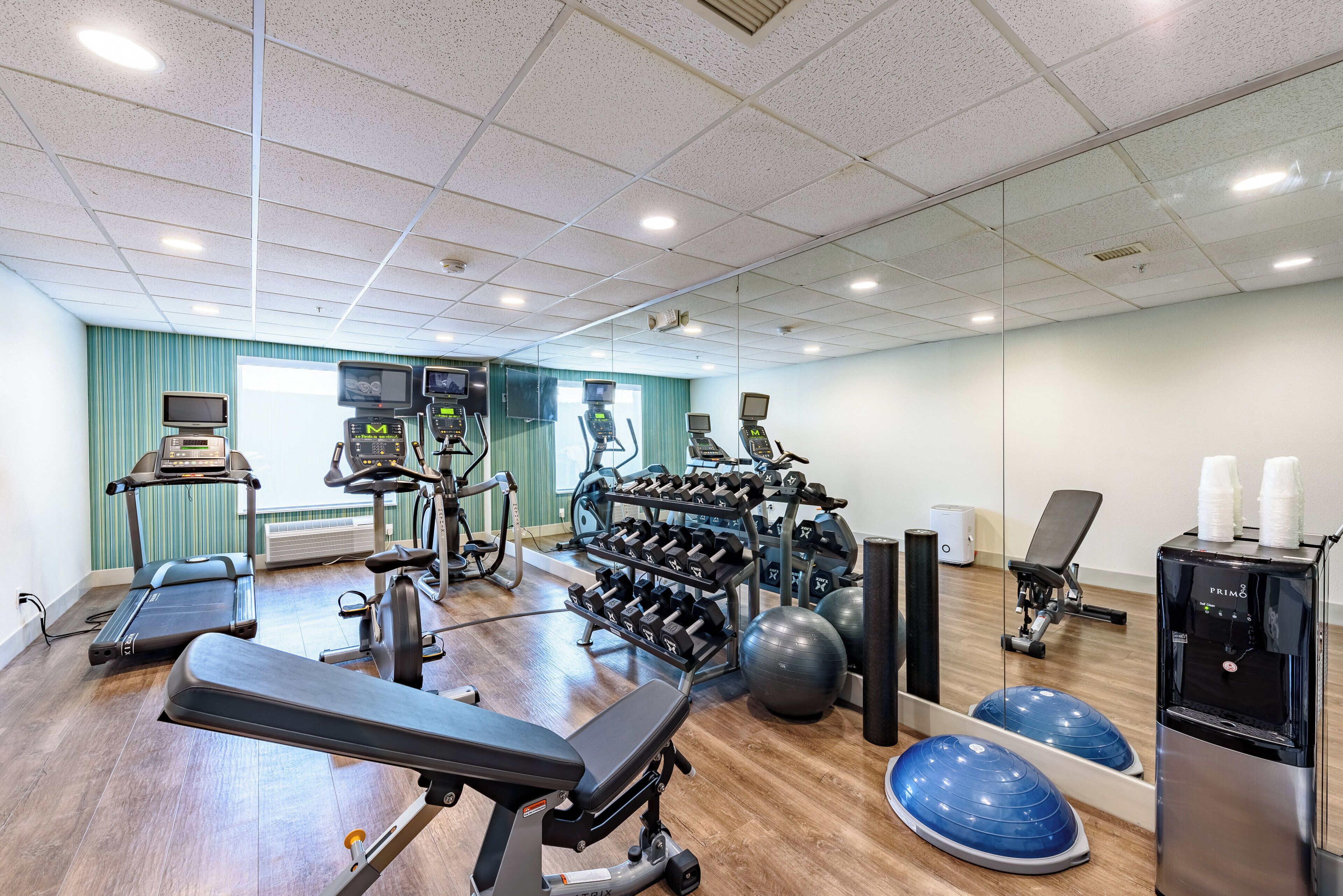 A gym with exercise equipment, a treadmill, a rowing machine, and a water dispenser.