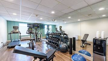 A gym with exercise equipment, a treadmill, a rowing machine, and a water dispenser.