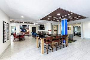 Un comedor amplio con una larga mesa y varias sillas, una zona de bar con asientos, y un rincón con cafetera.