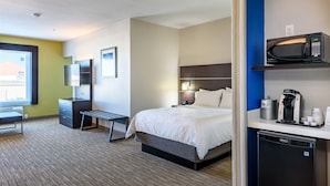 A hotel room with a bed, bedside table, desk, chair, TV, and a coffee machine. - Holiday Inn Express Hotel & Suites Bastrop by IHG (Bastrop)