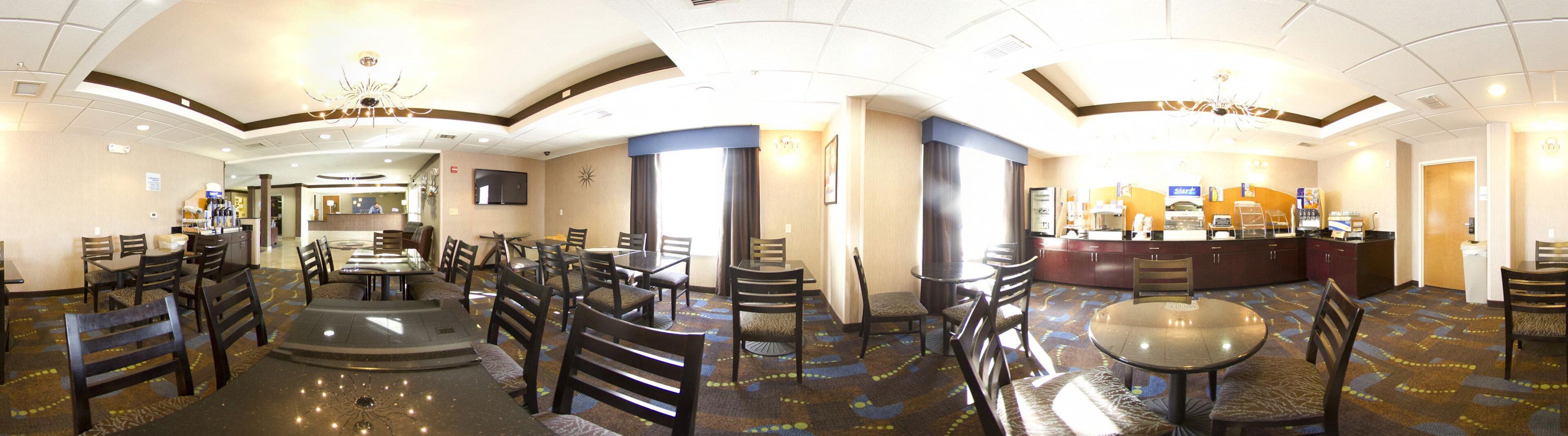 Un hall d’hôtel comprenant plusieurs tables et chaises, un comptoir de réception et une machine à café Starbucks.