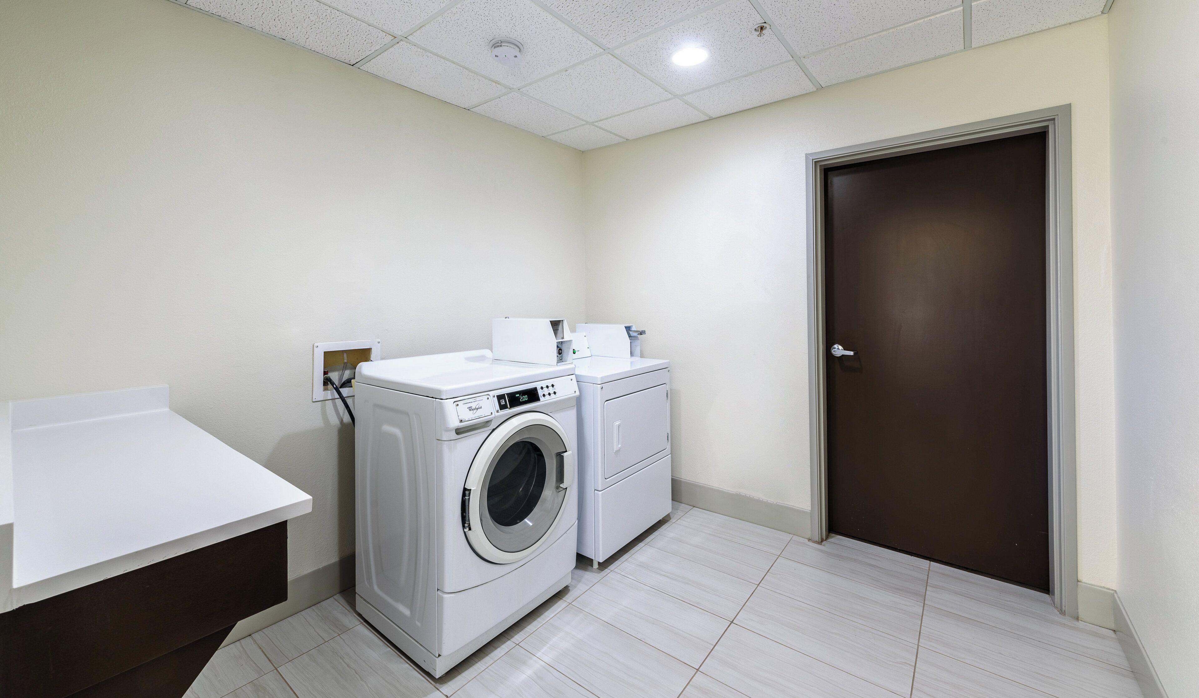 A laundry room with a washing machine, dryer, and a white countertop.