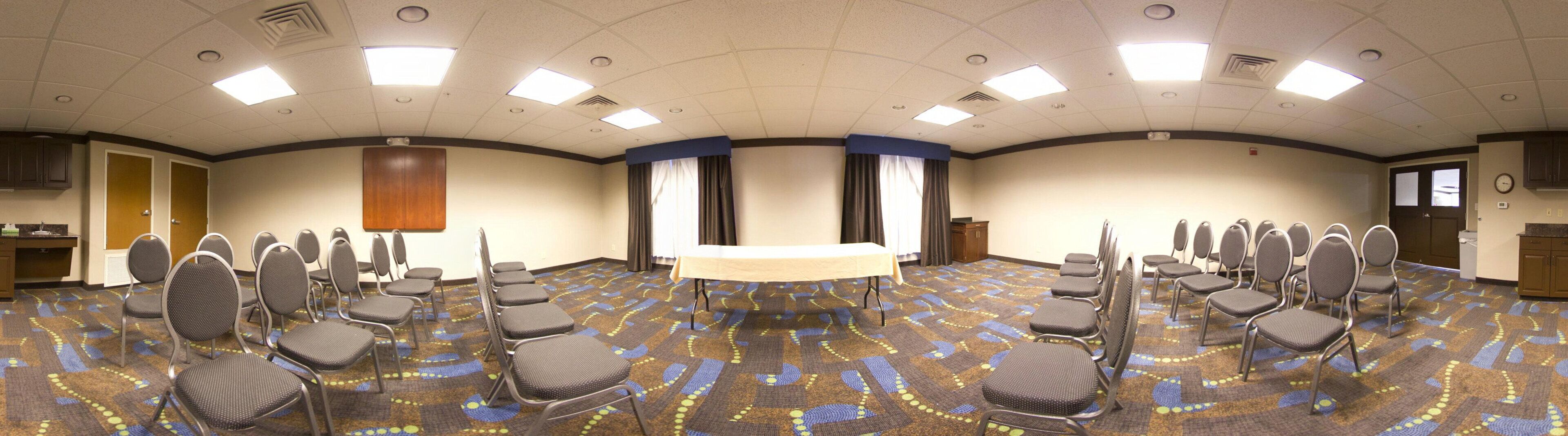 A conference room with a long table, multiple chairs, and a carpeted floor.