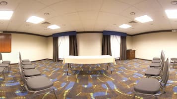 A conference room with a long table, multiple chairs, and a carpeted floor.