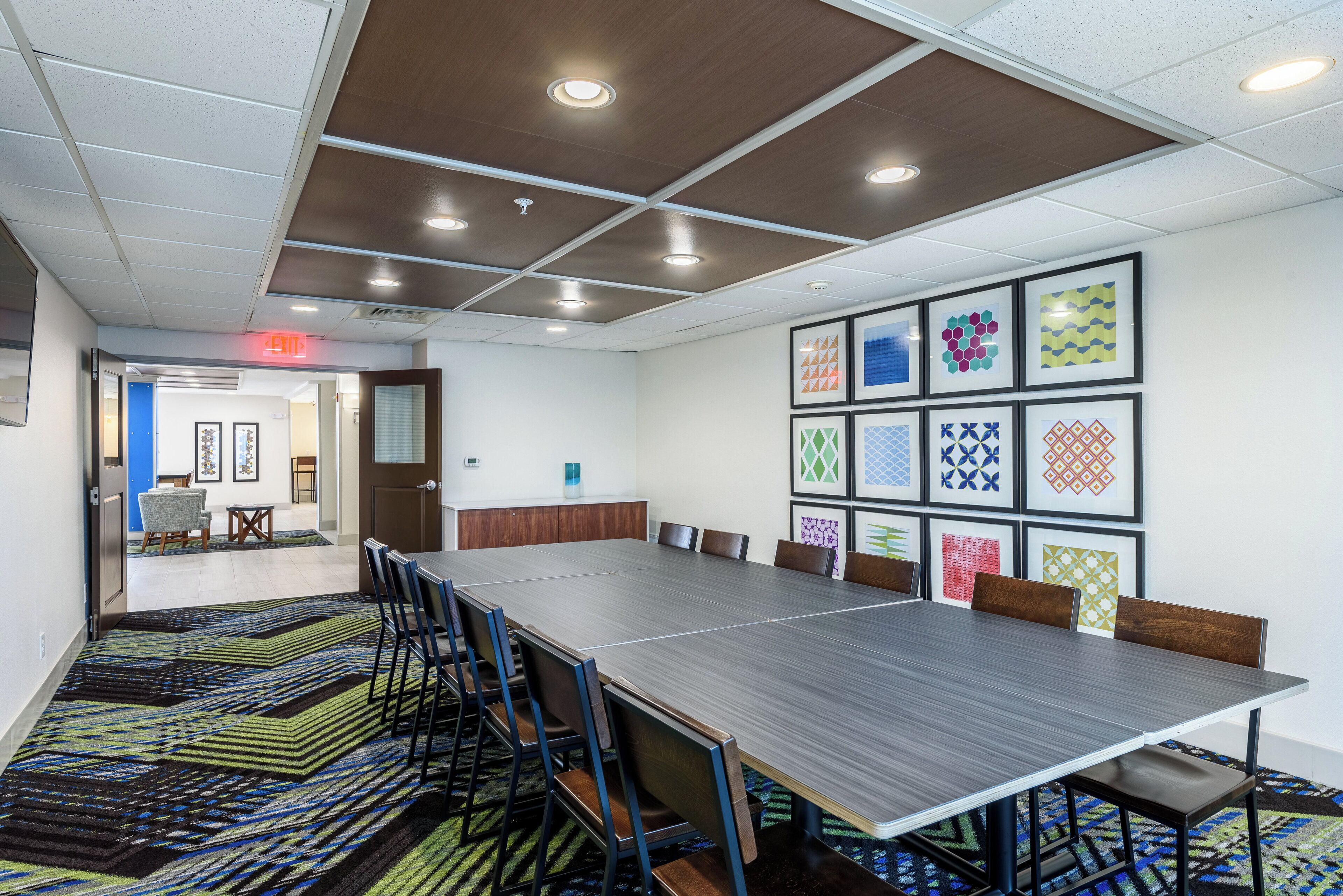 A conference room with a long table, chairs, and a patterned carpet.