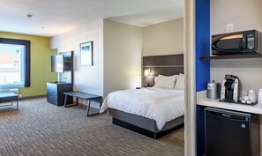 A hotel room with a bed, bedside table, desk, chair, television, and a coffee machine.
