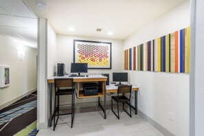 A modern office space with two desks, each with a computer and a printer. There is a framed abstract art piece on the wall above the desks. - Holiday Inn Express Hotel & Suites Bastrop by IHG (Bastrop)