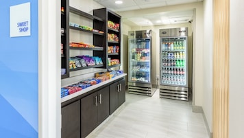 A hallway with a snack display and two refrigerated beverage dispensers.