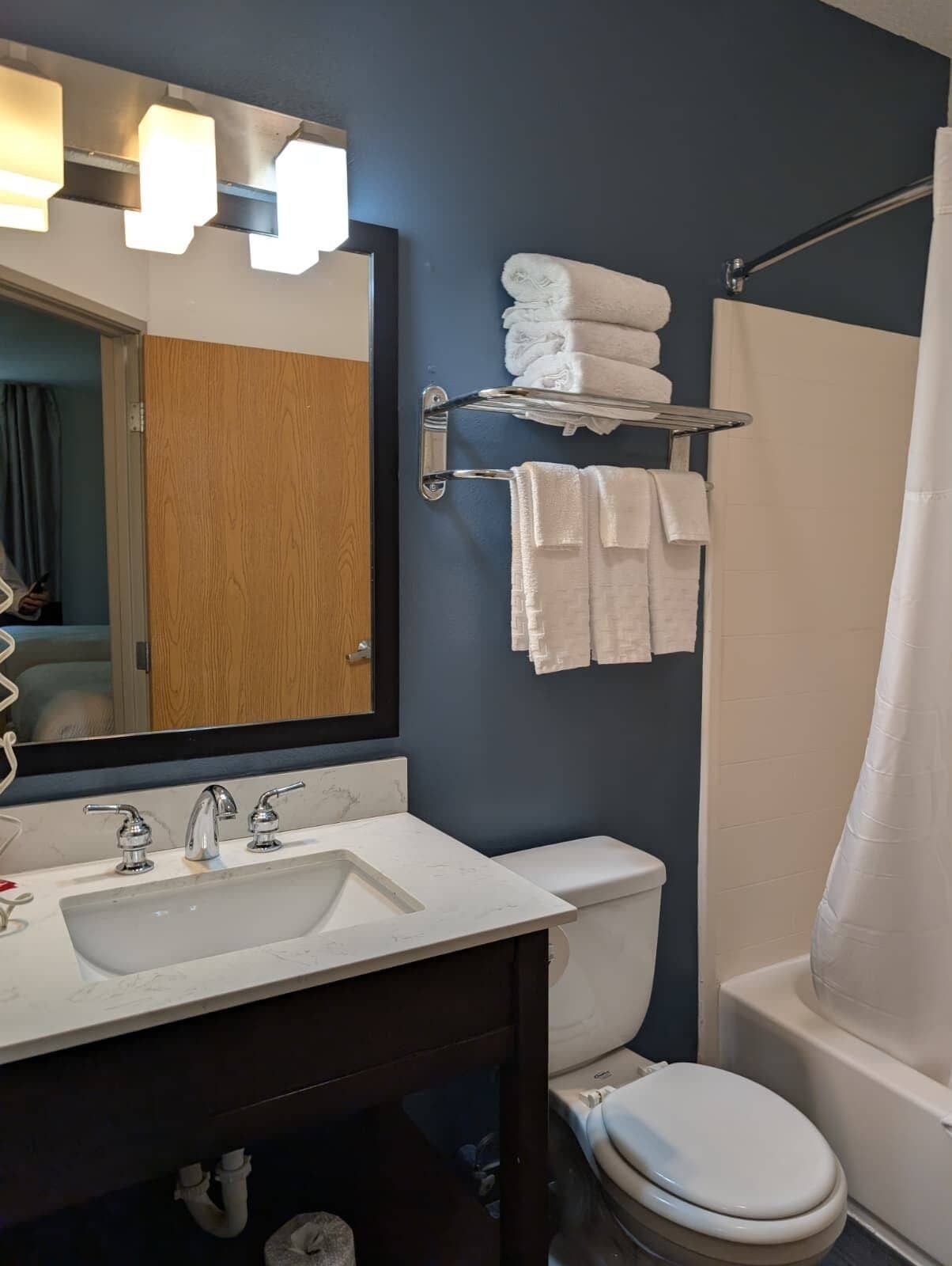 A bathroom with a sink, mirror, towel rack, and toilet.