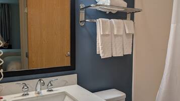 Une salle de bain équipée d’un lavabo, d’un miroir, d’un porte-serviettes et de toilettes.