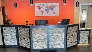 A reception desk with a world map, a black chair, and a laptop.
