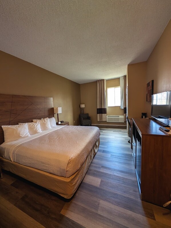 A hotel room with a large bed, a desk, and a television.