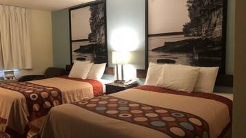 Een hotelkamer met twee bedden, elk met een beddekleed met een patroon, een nachtkastje met een lamp, en een groot, ingelijst beeld aan de muur.
