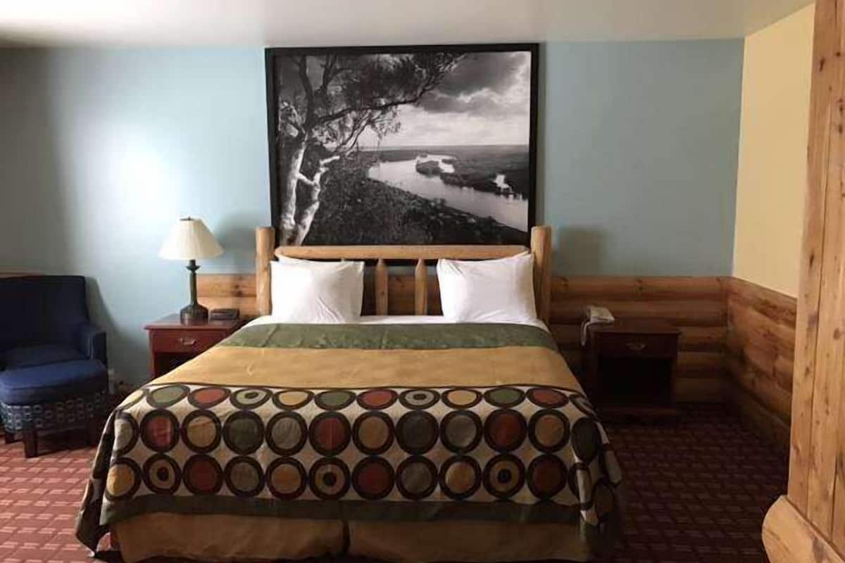 Een hotelkamer met een bed, nachtkastje, lamp en stoel.