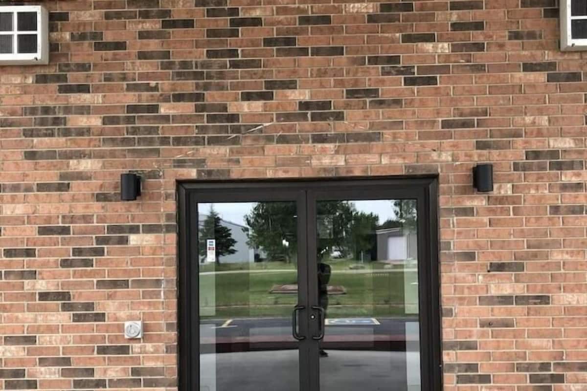 Een bakstenen gebouw met een grote glazen deur en een klein raam links.