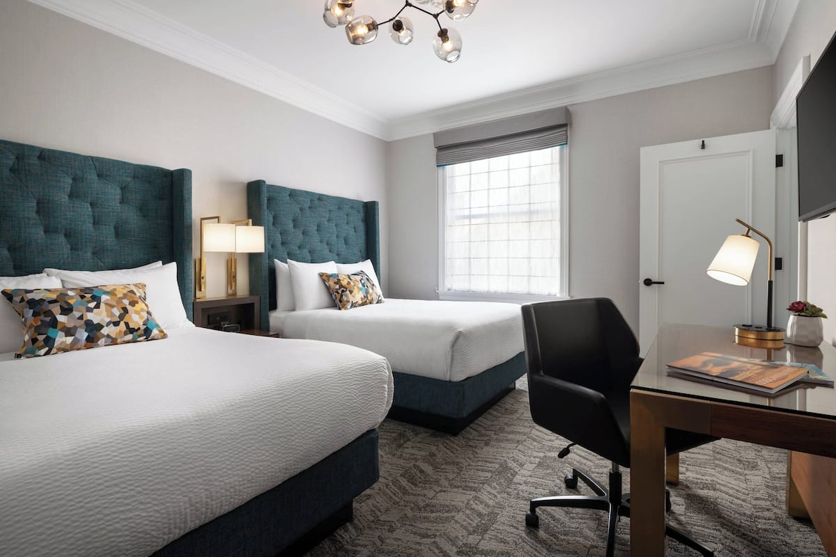 Une chambre d’hôtel avec deux lits, un bureau et une chaise.
