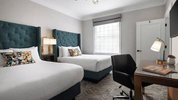 Habitación de hotel con dos camas, un escritorio y una silla.