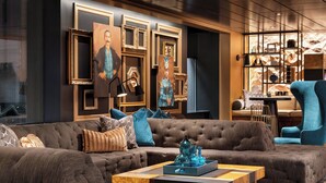 Een moderne woonkamer met een grote hoekbank, een salontafel en een wand versierd met ingelijste kunstwerken en een geometrisch wandrek.