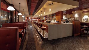 Een moderne bar met een lange toonbank, meerdere krukken en een gepolijste vloer.