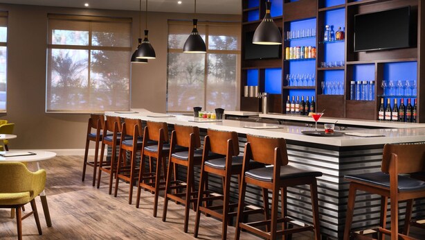 A bar area with a long counter, multiple bar stools, and a television mounted on the wall. - Residence Inn By Marriott Anaheim Resort Area (Garden Grove)