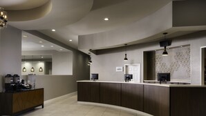 A modern reception area with a curved counter, recessed lighting, and a coffee machine. - Residence Inn By Marriott Anaheim Resort Area (Garden Grove)