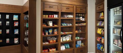 Una tienda de comestibles con estantes de madera repletos de refrigerios, bebidas y productos envasados.