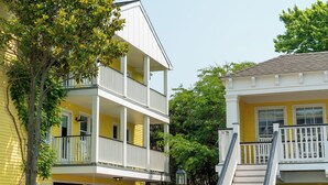 A yellow building with a white balcony and a staircase leading to a second floor. - The Star Inn (Cape May)
