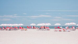 A beach with rows of pink and white beach chairs and umbrellas. - The Star Inn (Cape May)