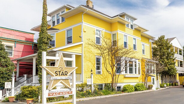A yellow building with a sign indicating it's a motel, inn, and coffee shop. - The Star Inn (Cape May)